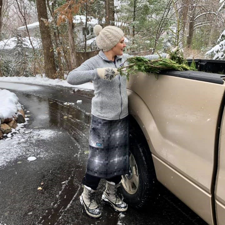 A woman wearing a NorSari while loading evergreen branches into a pickup on a snowy day