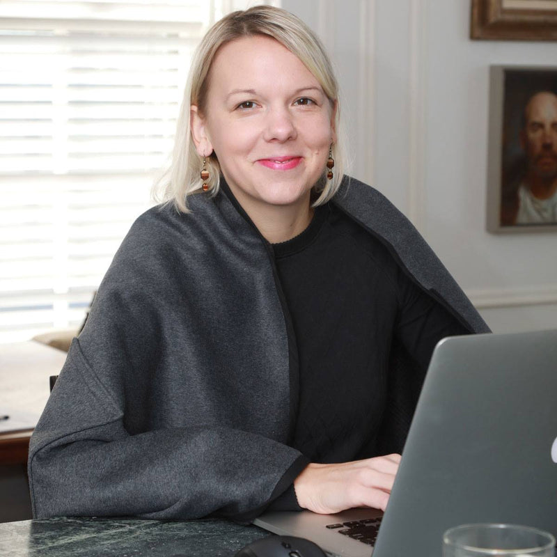 A woman using a NorSari as a shoulder layer while working at a laptop